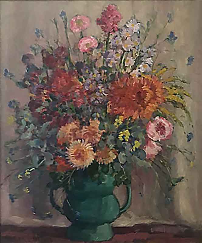 An arrangement of varying flowers in multiple colours in a green two-handled jug.